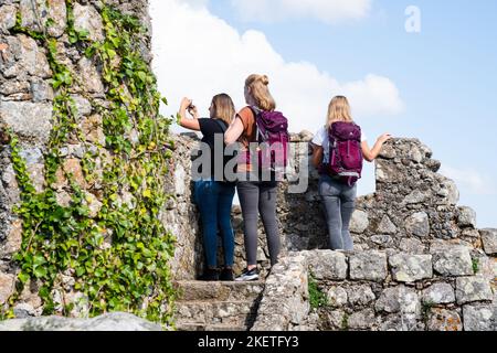 Touristen klettern auf die befestigten Mauern und Türme der maurischen Burg der Mauren aus dem 10.. Jahrhundert (Castelo dos Mouros) oberhalb von Sintra, Portugal. Stockfoto