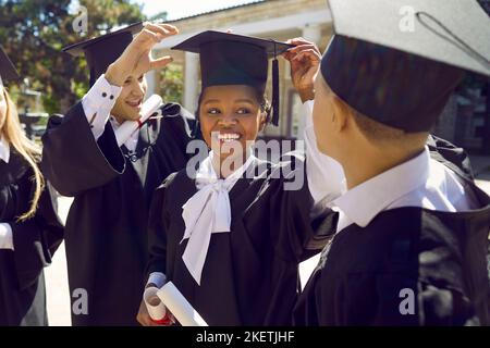Glückliche, vielfältige Studenten in akademischen Kappen, die Spaß an ihrem Abschlusstag haben Stockfoto