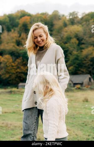 Eine Mutter geht im Herbst mit ihrer kleinen Tochter auf dem Land. Stockfoto