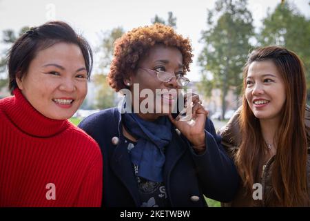 Drei reife Frauen zusammen in einem Park, Freundschaft zwischen Menschen unterschiedlicher Ethnien Stockfoto