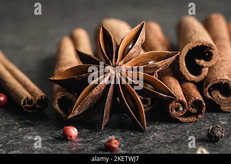 Aromatische Zimtschnecken und Anise auf schwarzem Tisch, Nahaufnahme. Stockfoto