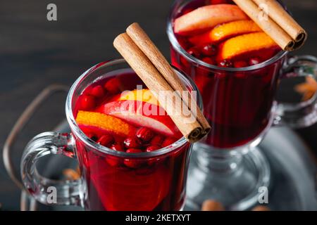 Zwei Gläser mit heißem Glühwein mit Orange und Gewürzen auf Holzboden. Heiße Getränke im Winter und Herbst Stockfoto