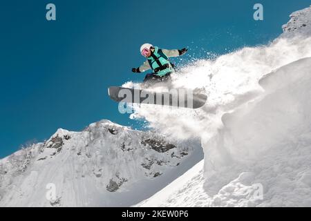 Schnelle Mädchen Snowboarder springt vom Sprungbrett hoch in den Bergen. Wintersportkonzept Stockfoto