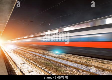 Bei Nacht am Hochgeschwindigkeitsbahnhof vorbeifahren. Stockfoto