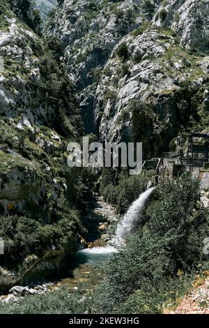 Altes kleines Wasserkraftwerk versteckt zwischen den Felsen der großen Berge neben dem Wasser des Flusses, ruta del Cares asturias, spanien Stockfoto