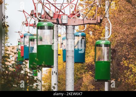 Bunte Seilbahnkabinen im Herbst Kharkiv Stadt Vergnügungspark mit gelben Blättern auf Bäumen Stockfoto