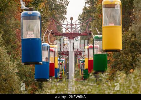 Bunte Seilbahnkabinen im Herbstgrün im Kharkiv Stadtvergnügungspark Stockfoto