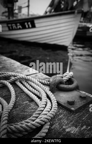 Ein Schiff ist mit einem dicken Seil an einem Poller im Hafen befestigt Stockfoto