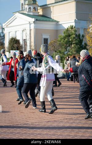 Bendery, Moldawien - 12. November 2022: Menschen tanzen moldawischen Tanz. Männer und Frauen in nationalen Kostümen tanzen am Vorabend den wunderschönen moldawischen chora-Tanz Stockfoto