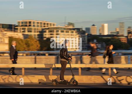 Ein Mann, der während der Hauptverkehrszeit mit einem E-Scooter über die London Bridge fährt. Fahren eines privaten E-Scooters ist illegal, abgesehen von auf Privateigentum in Stockfoto