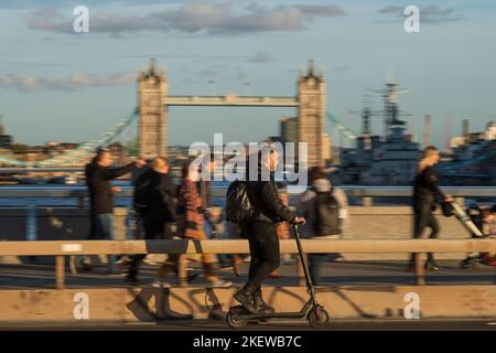 Ein Mann, der während der Hauptverkehrszeit mit einem E-Scooter über die London Bridge fährt. Fahren eines privaten E-Scooters ist illegal, abgesehen von auf Privateigentum in Stockfoto