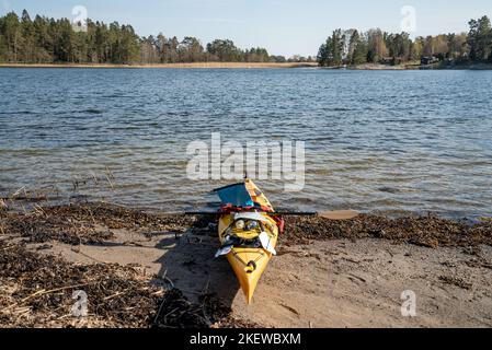 Das Gelbe Meer Kajak hielt am Ufer einer Insel im Stockholmer Archipel, Schweden. Gelbes Kajak am Strand. Stockfoto