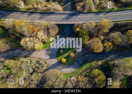 Luftaufnahme eines kleinen Verkehrskreisel auf einer Landstraße mit herbstlichen (Herbst-) bunten Bäumen. Stockfoto