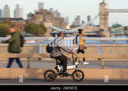 Ein Mann, der während der Hauptverkehrszeit ein E-Bike über die London Bridge, London, Großbritannien, fährt. 18 Okt 2022 Stockfoto