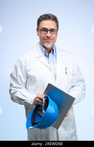 Ingenieur mittleren Alters in Laborkittel mit Helm. Wissenschaftler, Architekt mit Tablet. Mittlerer Erwachsener, Mann im reifen Alter, glücklich lächelnd. Porträt isoliert auf Weiß. Stockfoto