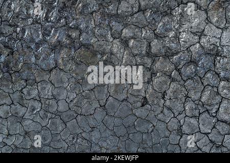 Schwarze gerissene Textur der tiefschwarzen Oberfläche von Kohle oder Ruß aus nächster Nähe. Schwarze Landstruktur und Hintergrund Stockfoto