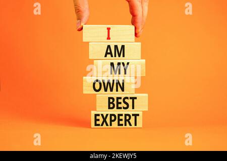 Ich bin mein eigenes bestes Expertensymbol. Konzeptworte Ich bin mein eigener bester Experte für Holzblöcke auf einem schönen orangen Tisch mit orangefarbenem Hintergrund. Geschäftsmann Hand Stockfoto