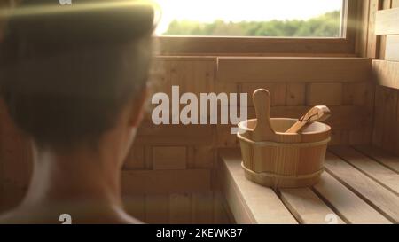 Frau, die sich in der heißen Sauna entspannt und schwitzt. Echter, authentischer Saunamoment. Stockfoto