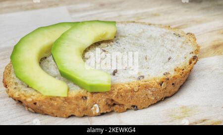 Frisch zubereitetes vegetarisches Sandwich mit Vollkornbrot, Luzerne gekeimt und Avocado auf rustikalem Holztisch, Draufsicht. Gesunde Ernährung Hintergrund Stockfoto