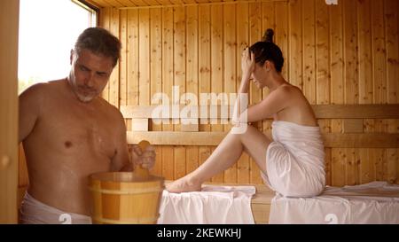 Paar entspannen sich in der heißen Sauna. Authentischer, echter Saunamoment. Stockfoto