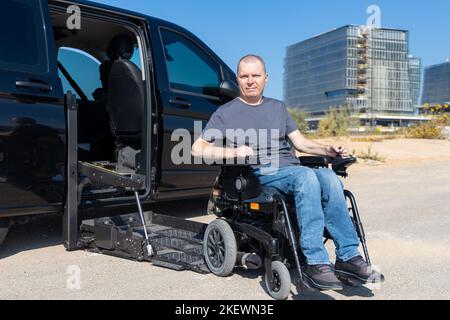 Behinderter Mann im Rollstuhl, der auf dem Autolift steht Stockfoto