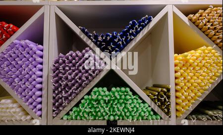 Bunte Stabkerzen auf Regalen angeordnet und in einem Kerzengeschäft nach Farben sortiert. Stockfoto