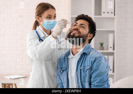 Augenarzt legt im Krankenhaus Tropfen in das Auge des jungen Mannes Stockfoto