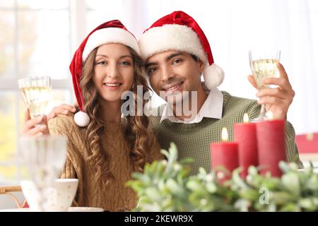 Liebevolles Paar mit Gläsern Champagner in der Küche am Heiligabend Stockfoto