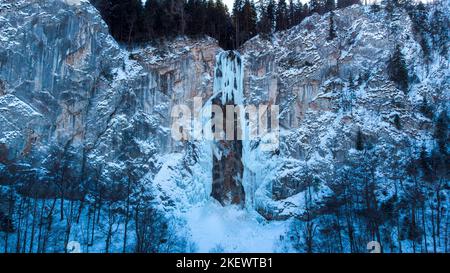 Luftdrohnenansicht des gefrorenen Wasserfalls mit etwas Wasser, das durchläuft. Wunderschöne und magische Winterurlaubslandschaft für Naturliebhaber. Stockfoto