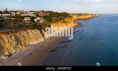 Luftdrohnenaufnahme von Menschen am Strand bei einem wunderschönen Sonnenuntergang. Fantastische, lebendige Farben. Algarve, Portugal. Klares Wasser. Urlaub und Urlaub. Stockfoto