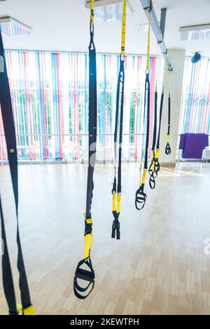 TRX Fitnessbänder für das Arbeiten mit eigenem Gewicht. TRX-Fitnessgurte hängen im leeren Fitnessstudio Stockfoto