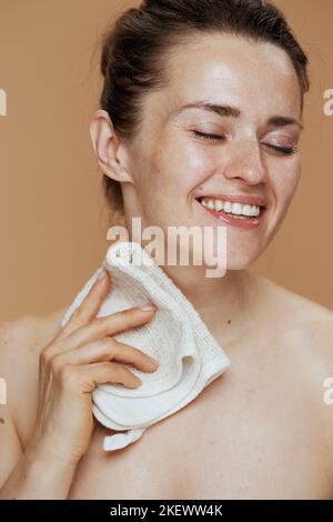 Lächelnde Frau mittleren Alters mit Handtuch waschen Gesicht. Stockfoto