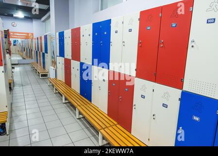 Rote Schließfächer in allgemeinen Umkleideraum mit Holzbank rot blau weiß Stil Stockfoto