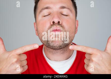 Ein Mann faltete Lippen und schloss die Augen mit einem zarten Lächeln, der einen Kuss geben wollte Stockfoto