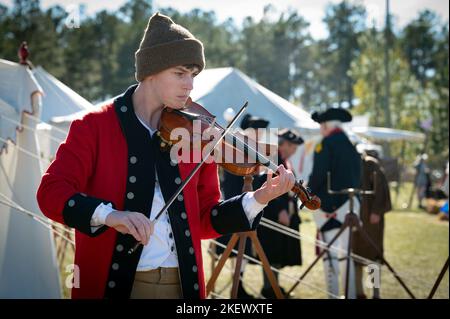 Kershaw, South Carolina, USA. 13.. November 2022. Fans des Revolutionären Krieges und leidenschaftliche Schauspieler stellen die Schlacht von Camden, SC, nach, sodass Besucher während des Krieges um die Unabhängigkeit von der britischen Herrschaft lebendige Geschichte erleben können. Die Schlacht von Camden, die 1780 ausgetragen wurde, war eine von mehreren verheerenden Niederlagen, die die Amerikaner in den frühen Phasen der britischen Militäroffensive im Süden erlitten haben. Im Bild: Ein Musiker spielt Geige, die damals populär war. (Bild: © Robin Rayne/ZUMA Press Wire) Stockfoto