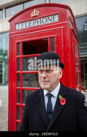 englischer Gentleman in Melone Hut vor der traditionellen britischen roten Telefonbox Stockfoto