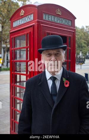 englischer Gentleman in Melone Hut vor der traditionellen britischen roten Telefonbox Stockfoto