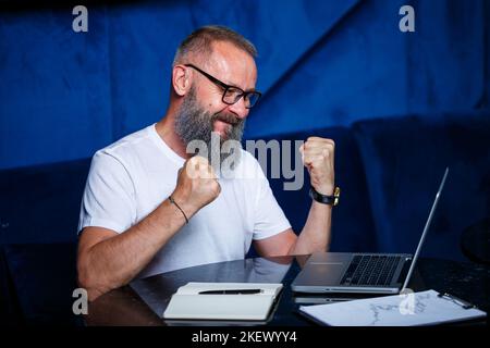 Erwachsener männlicher Mentor, Regisseur, Geschäftsmann in Brille und eine Anzug, die Dokumente beim Sitzen am Tisch studiert. Konzept des Arbeitstages Stockfoto