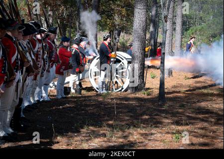 Kershaw, South Carolina, USA. 13.. November 2022. Fans des Revolutionären Krieges und leidenschaftliche Schauspieler stellen die Schlacht von Camden, SC, nach, sodass Besucher während des Krieges um die Unabhängigkeit von der britischen Herrschaft lebendige Geschichte erleben können. Die Schlacht von Camden, die 1780 ausgetragen wurde, war eine von mehreren verheerenden Niederlagen, die die Amerikaner in den frühen Phasen der britischen Militäroffensive im Süden erlitten haben. Im Bild: Britische Soldaten stehen für einen Konflikt auf, während ein Kanon die Runden schießt. (Bild: © Robin Rayne/ZUMA Press Wire) Stockfoto