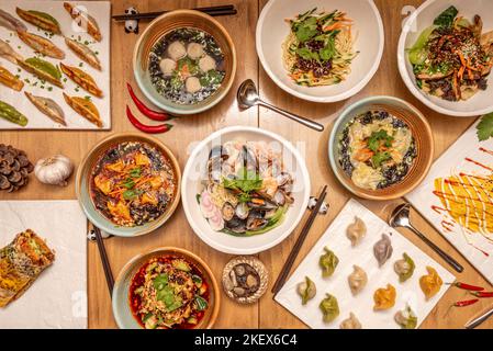 Typische japanische Speiserezepte mit verschiedenen Ramen, frittierten Gyozas, gekochten Gyozas und hölzernen Essstäbchen auf Pandabären Stockfoto