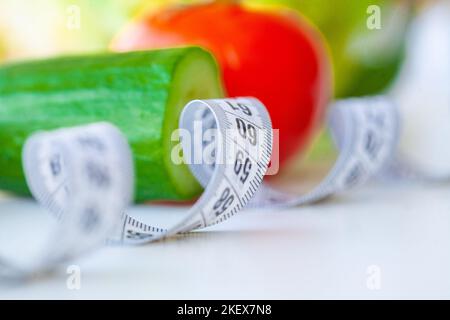 Diät. Fitness und gesunde Ernährung Konzept. Ausgewogene Ernährung mit Gemüse. Frische, grüne Gemüse, Maßband auf weißem Hintergrund. Nahaufnahme Stockfoto