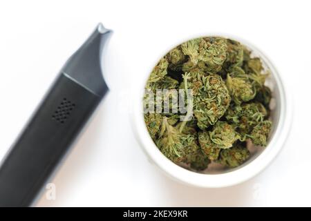 Cannabis flos, medizinisches Marihuana in weißem Behälter neben Verdampfer, sichere Art und Weise, Medizin zu nehmen Stockfoto