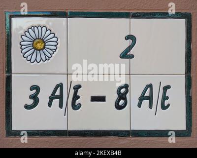 Teller mit Haus- oder Wohnungsnummern und Buchstaben.Traditionelles spanisches Betonzeichen von bunten Keramikfliesen. Hintergrund aus gemalten Azulejos. Stockfoto