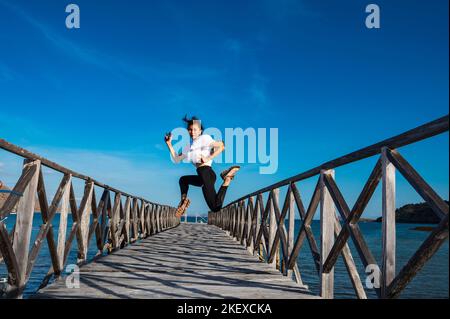 Frau, die auf einem Pier auf der östlichen Insel Nusa Tenggara in Komodo springt Stockfoto