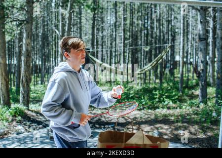 Teen boy mit Badminton draußen im Wald Stockfoto