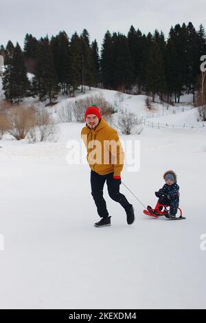 Vater tragen Sohn auf einem Schneescooter Stockfoto