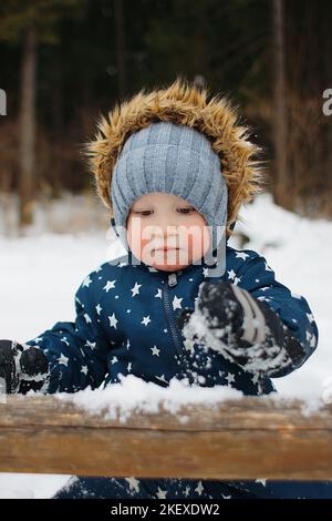 Junge macht Schneemann im Wald Stockfoto