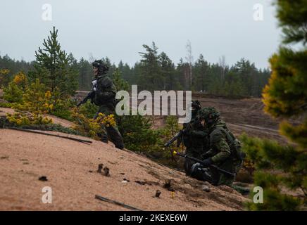 Finnische Soldaten, die 6. Squadron, 9. Kavallerieregiment, 3. Brigade Combat Team, 1. Kavalleriedivision (3-1 ABCT) unterstützen, operativ der 1. Infanterie Division (1 ID) zugewiesen, laufen während Hammer 22, einer jährlichen kombinierten Streitkräfteübung, die von und neben Finnlands Armeehauptquartier, der Panzerbrigade, der Pori Brigade, durchgeführt wird, über einen Liegeplatz Karelia Brigade, UTI Jaeger Regiment und Logistikabteilung der Streitkräfte, in Niinisalo, Finnland, 10. November 2022. Der 3-1 ABCT arbeitet unter anderem unter der ID 1 stolz mit Verbündeten und regionalen Sicherheitspartnern zusammen, um Kampfcredi zu liefern Stockfoto