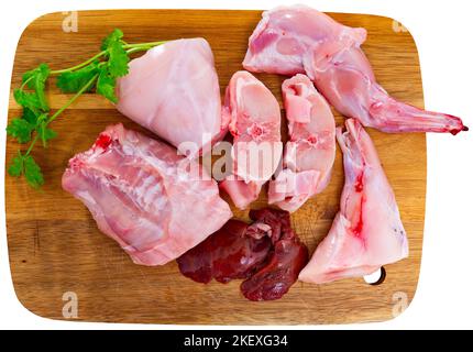 Roh geschnittenes Kaninchen, das auf einem Holzschneidebrett mit Gewürzen liegt Stockfoto