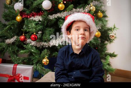 Frustriertes Kind in den weihnachtsferien sieht Sie sitzen auf einem Boden zu Hause in der Nacht Stockfoto